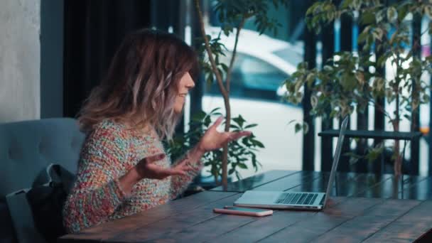 Felice blogger ragazza parlando sul computer portatile seduto in caffè — Video Stock