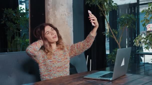 Glückliche Bloggerin telefoniert, während sie in einem Café sitzt — Stockvideo
