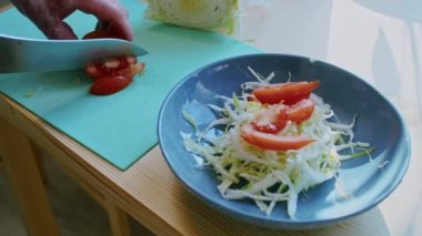 Evde yemek pişirmek. Erkek eli domatesi kesiyor, yakın plan. salata hazırlama.