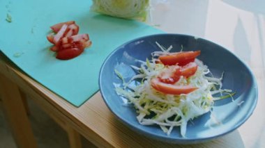 Evde yemek pişirmek. Bir adamın elleri bir tabağa domates döker, yakın plan. salata hazırlama.