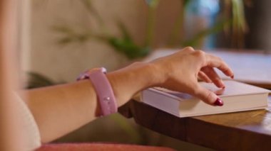 Bir kafede telefonla konuşan mutlu genç bir kadın, bir kitaba eliyle dokunuyor. Kafede harika zaman geçirdik..