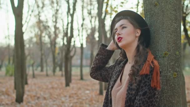 Feliz mulher brincalhão em casaco, chapéu e cachecol no parque de outono — Vídeo de Stock