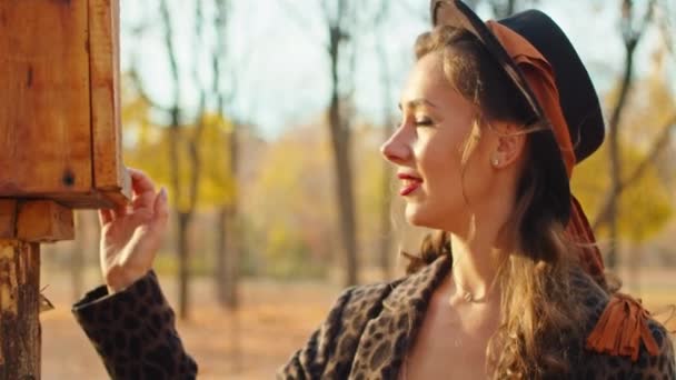 Feliz mujer juguetona en abrigo, sombrero y bufanda en el parque de otoño — Vídeo de stock