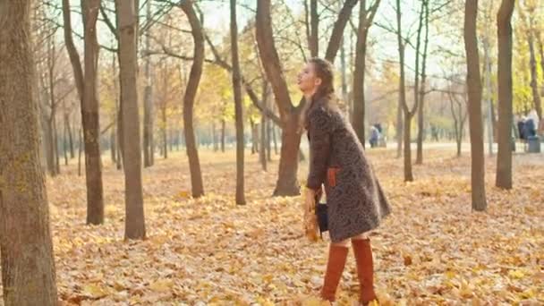 Szczęśliwa zabawna kobieta w płaszczu, kapeluszu i szaliku w jesiennym parku — Wideo stockowe