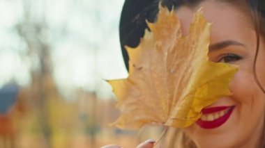 Sonbahar parkında ceketli, şapkalı ve atkılı mutlu bir kadın.