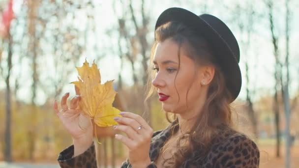 Glad lekfull kvinna i rock, hatt och halsduk i höstparken — Stockvideo