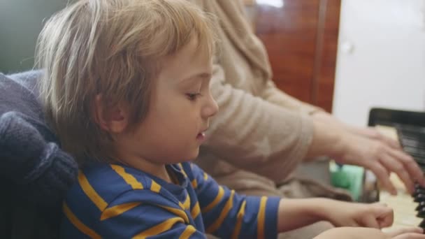 Petit enfant heureux de 2 ans apprenant à jouer du piano à la maison avec grand-mère. — Video