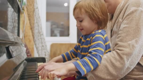 Petit enfant heureux de 2 ans apprenant à jouer du piano à la maison avec grand-mère. — Video