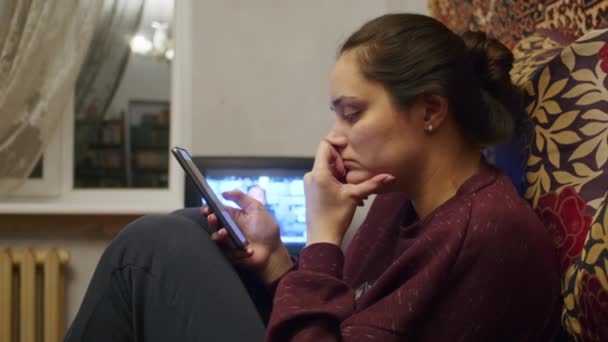 Een verdrietig meisje kijkt met een smartphone naar het vreselijke nieuws over het Russische offensief op het grondgebied van Oekraïne. Nieuws over spanningen tussen Oekraïne en Rusland. Russische agressie. De dreiging van oorlog — Stockvideo