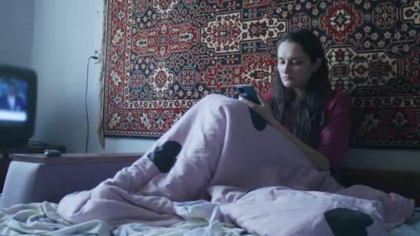Een verdrietig meisje kijkt met een smartphone naar het vreselijke nieuws over het Russische offensief op het grondgebied van Oekraïne. Nieuws over spanningen tussen Oekraïne en Rusland. Russische agressie. De dreiging van oorlog — Stockvideo
