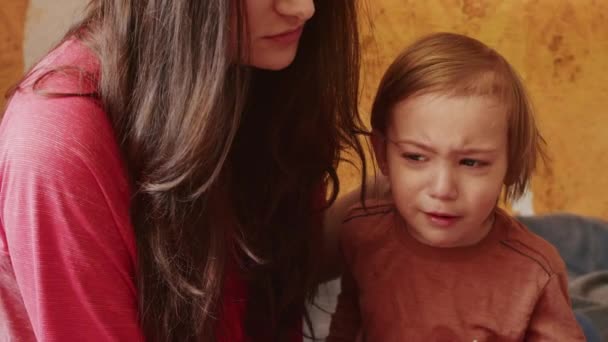 Krivoy Rog, UKRAINE - FEBRUARI 2022 een verdrietig meisje kijkt naar het verschrikkelijke nieuws op de smartphone over het Russische offensief op het grondgebied van Oekraïne. een klein kind huilt naast zijn moeder vanwege — Stockvideo