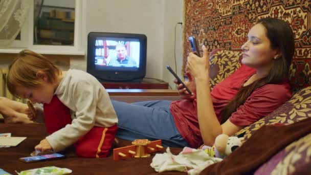 Een verdrietig meisje met haar familie, moeder en klein kind, kijkt naar het verschrikkelijke nieuws op de smartphone over het Russische offensief op het grondgebied van Oekraïne. Nieuws over spanningen tussen Oekraïne en Rusland — Stockvideo