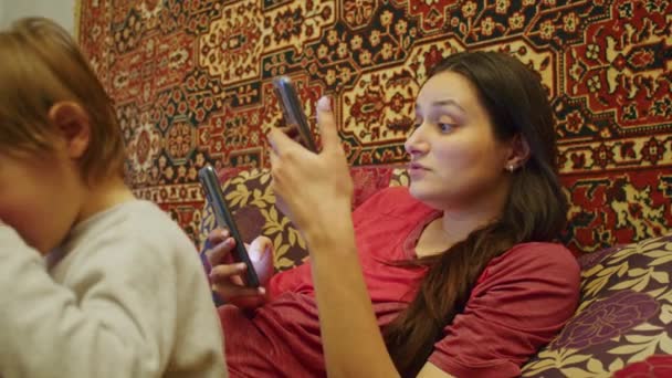 A sad girl with her family, mother and small child, looks at the terrible news on the smartphone about the Russian offensive on the territory of Ukraine. News about tensions between Ukraine and Russia — Stock Video