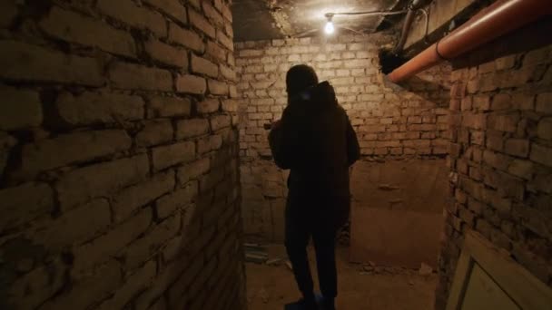 Een meisje in een verschrikkelijke staat doorzoekt een enge kelder om een mogelijke schuilplaats te vinden in het geval van een bomexplosie. Nieuws over spanningen tussen Oekraïne en Rusland. Russische agressie. De dreiging van oorlog. — Stockvideo