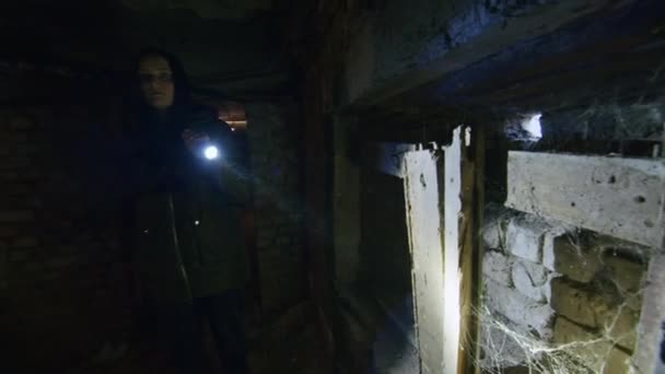 Uma rapariga num estado terrível procura numa cave assustadora para encontrar um possível abrigo em caso de explosão de uma bomba. Notícias sobre tensões entre a Ucrânia e a Rússia. Agressão russa. A ameaça da guerra. — Vídeo de Stock