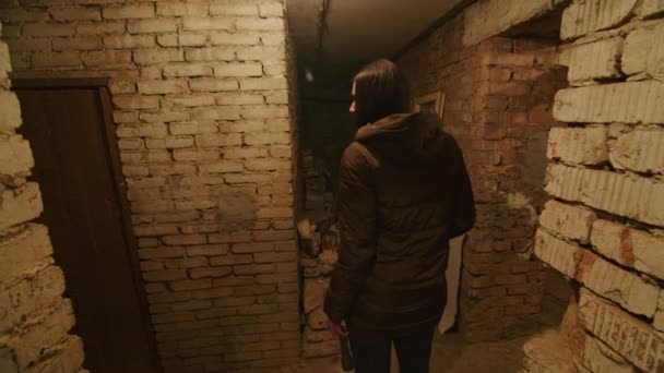 Dziewczyna w okropnym stanie przeszukuje straszną piwnicę, by znaleźć schronienie w razie wybuchu bomby. Wiadomości o napięciach między Ukrainą a Rosją. Rosyjska agresja. Zagrożenie wojną. — Wideo stockowe