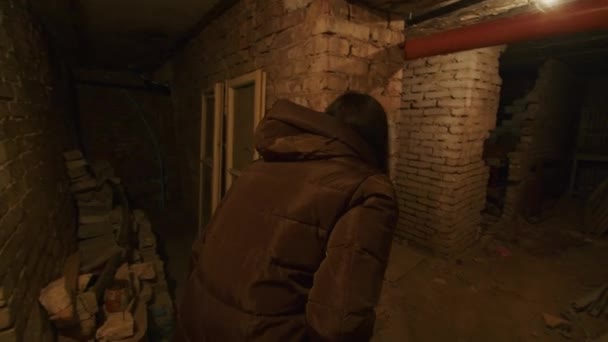 En flicka i en hemsk stat söker igenom en skrämmande källare för att hitta ett eventuellt skydd i händelse av en bomb explosion. Nyheter om spänningar mellan Ukraina och Ryssland. Rysk aggression. Hotet om krig. — Stockvideo