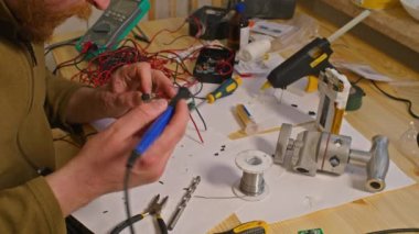 Kryvyi Rih, Ukrayna - Rusya 'nın Ukrayna' ya karşı 2022 yılındaki savaşı. Elektrik bankalarının yetersizliğinden dolayı elektrikçi Ukrayna Silahlı Kuvvetleri için ev yapımı şarj aletleri ve elektrik bankalarını lehimliyordu.