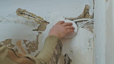 Erkek bir elektrikçi yenilemeden önce bir apartmanda tesisat işi yapıyor..
