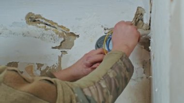 Erkek bir elektrikçi yenilemeden önce bir apartmanda tesisat işi yapıyor..