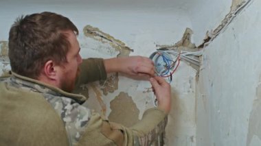 Erkek bir elektrikçi yenilemeden önce bir apartmanda tesisat işi yapıyor..