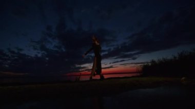 Cadılar Bayramı kostümü içinde mutlu genç bir kadın gün batımında doğada dans ediyor, mistik görüntüler..