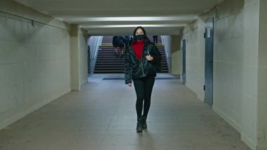 Sağlık maskeli genç bir kadın alt geçitten geçiyor. Karantina süresi. anti-covid ölçümler.