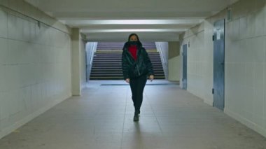 Sağlık maskeli genç bir kadın alt geçitten geçiyor. Karantina süresi. anti-covid ölçümler.