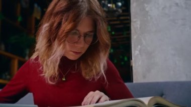 Genç, üzgün, ev ödevlerinden bunalmış bir kız öğrenci bir kafede dizüstü bilgisayarla oturuyor..