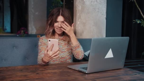 Happy girl blogger talking on the phone while sitting in a cafe — Stock Video