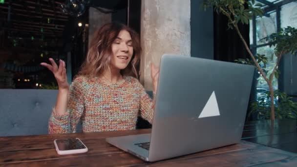 Feliz blogger chica hablando en el ordenador portátil sentado en la cafetería — Vídeo de stock