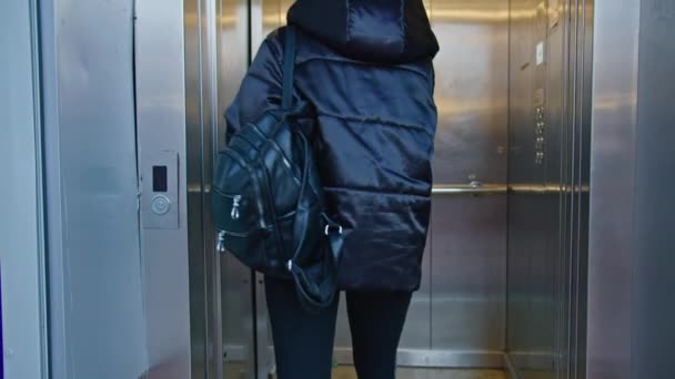 Tıbbi maskeli genç bir kadın asansörde oturuyor. Karantina süresi. anti-covid ölçümler. — Stok video