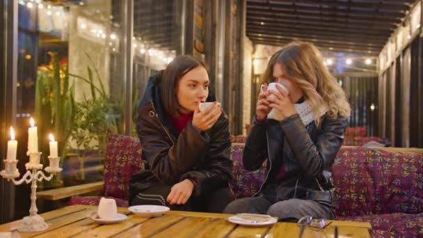 Dvě šťastné ženy spolu tráví čas v kavárně, restauraci, romantickém večeru při svíčkách, lehké atmosféře, životním stylu. pít kávu společně. — Stock video