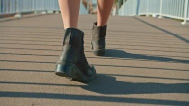 Bir kadının bacakları şehir parkında köprü boyunca yürür. sonbahar yaz dönemi.