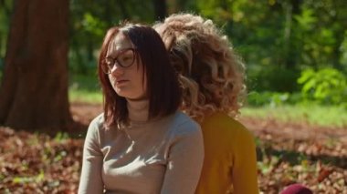 İki mutlu genç kadın şehir parkında harika vakit geçiriyor, bir kız gitar çalıyor, ikincisi ise müziğin ve ağaçların gürültüsünün tadını çıkarıyor. sonbahar yaz dönemi.