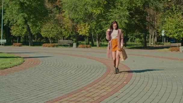 안경을 쓴 행복 한 여자가 공원을 산책 한다. 가을철. — 비디오