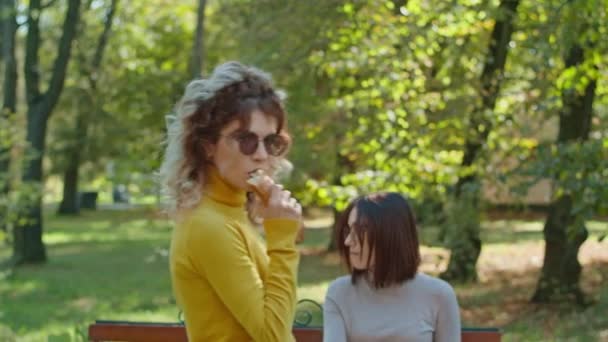 Een jonge vrolijke vrouw die stokbrood eet in het stadspark. Veel plezier samen. jeugd, rust, zomer of herfst park. — Stockvideo