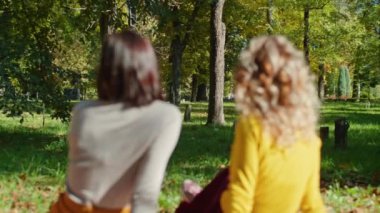 İki mutlu genç kadın şehir parkında otururken eğleniyor. Mutlu gençlik hayatı.