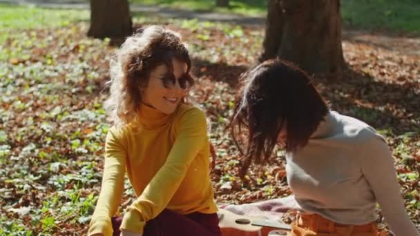 To glade unge kvinder har det sjovt sidder i byens park. lykkelige unge liv. – Stock-video