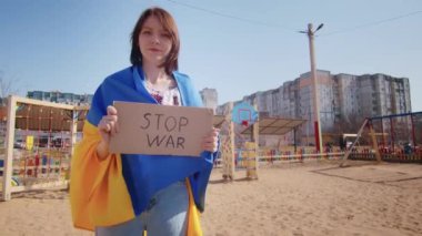 Ukrayna bayrağı ve bir işaret taşıyan neşeli bir Ukraynalı kadının portresi. Kız, savaştan kalan kocasını bekliyor. Rusya ile Ukrayna arasındaki savaş.