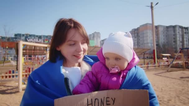 Portrait of a joyful Ukrainian woman holding a child and a Ukrainian flag. The girl is waiting for her husband from the war. War between Russia and Ukraine. — Stock Video