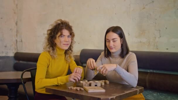 Duas mulheres felizes passam tempo juntas no café, restaurante, jogo de tabuleiro, atmosfera leve, estilo de vida. beber café juntos. — Vídeo de Stock