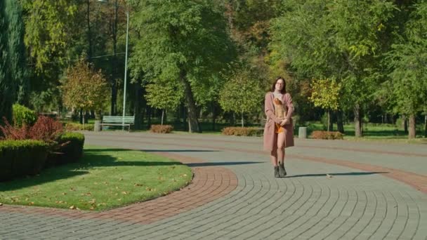 Μια νεαρή ευτυχισμένη γυναίκα με γυαλιά περπατάει στο πάρκο. Φθινοπωρινή περίοδος. — Αρχείο Βίντεο