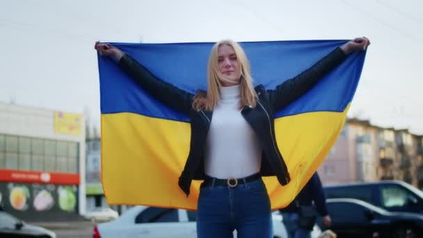 Retrato de uma mulher ucraniana alegre segurando uma bandeira ucraniana e um sinal. A rapariga está à espera do marido da guerra. Guerra entre a Rússia e a Ucrânia. — Vídeo de Stock
