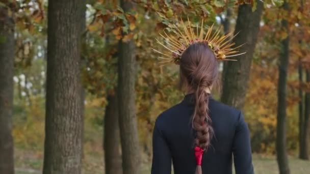 Młoda kobieta z makijażem Santa Muerte ubrana w czarną sukienkę śmierci spaceruje na tle jesiennych liści w lesie podczas zachodu słońca. Dzień Zmarłych czy koncepcja Halloween. — Wideo stockowe