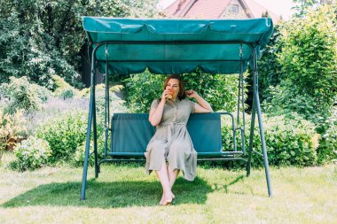 Yazın genç bir kız sıcak çay içer, salıncakta oturur, bahçesinde, çay en iyi sıcakta yardımcı olur, Prores422