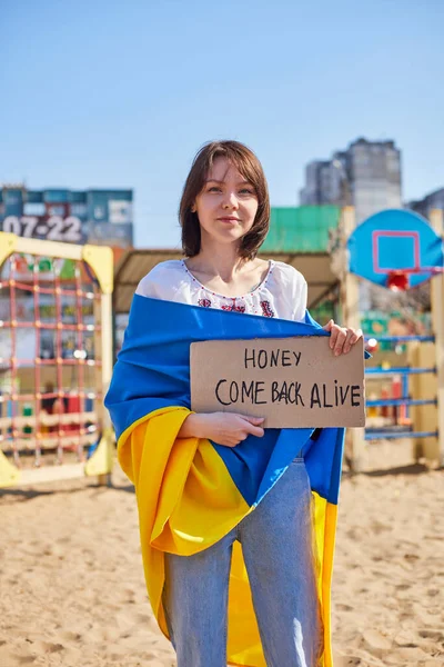 Çocuk ve Ukrayna bayrağı tutan neşeli bir Ukraynalı kadının portresi. Kız, savaştan kalan kocasını bekliyor. Rusya ile Ukrayna arasındaki savaş. — Stok fotoğraf