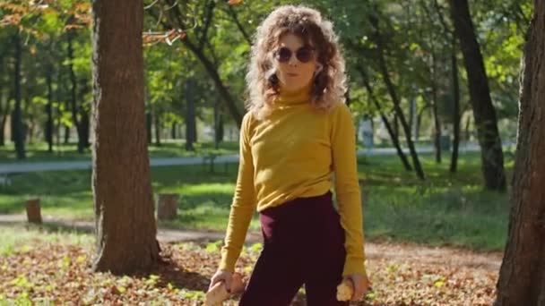 Een jonge vrolijke vrouw die stokbrood eet in het stadspark. Veel plezier samen. jeugd, rust, zomer of herfst park. — Stockvideo