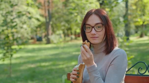 Fiatal boldog nő bagettet eszik a City Parkban. A lányok jól érzik magukat együtt. ifjúság, nyugalom, nyári vagy őszi park. — Stock videók