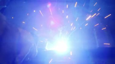 Kapalı çekimde, bir adam yaydan çıkan çelik yelek için plaka kaynatıyor. Ev yapımı zırh plakası. Fabrika işçisi metali kaynaklıyor. Adam kaynak yapıyor. Kaynak makinesi kullanarak argon veya elektrot ile kaynak yapmak. Kıvılcım ve